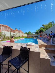 a swimming pool with two chairs and people sitting around it at Vivíana Hause Hospedaje in Cambyretá