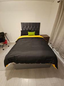 a bedroom with a black bed with a yellow pillow at Spacious, cozy double room 3 with amenities in Nottingham