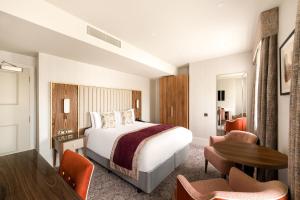 a hotel room with a bed and a table at voco The Clifton Folkestone by IHG in Folkestone