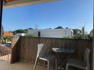 een patio met 2 stoelen en een tafel aan een hek bij Plage à 400 m Studio tout confort Terrasse Clim Parking in Hyères +25 foto's