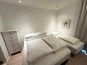 a white bedroom with two beds and a dresser at Naustavör 30 in Reykjavík