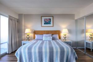 a bedroom with a large bed with two lamps at 1519 Ilikai Collection 9 Beachfront Resort recently upgraded in Honolulu