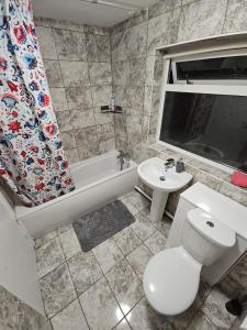 a bathroom with a toilet and a tub and a sink at Spacious single room in Nottingham +8 photos