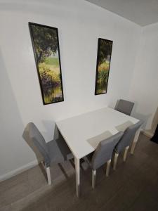 a white dining room table and chairs with paintings on the wall at Spacious single room in Nottingham +8 photos
