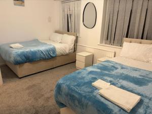 a bedroom with two beds and a mirror at Bella Homes-Spacious 4 bedroom Modern Town house Romford in Romford