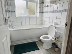 a bathroom with a toilet and a tub and a sink at Bella Homes-Spacious 4 bedroom Modern Town house Romford in Romford +28 photos