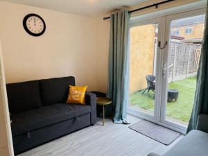 a living room with a couch and a clock on the wall at Bella Homes-Spacious 4 bedroom Modern Town house Romford in Romford