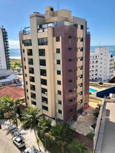 a tall building with palm trees in front of it at Caioba Apto Confortavel in Matinhos