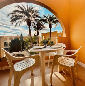 - une salle à manger avec une table, des chaises et des palmiers dans l'établissement Click&Guest - Golden Sands in Maspalomas, à San Fernando