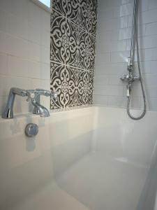 a bathroom with a tub with a shower and a tile wall at Milan Casa in Winnersh +29 photos