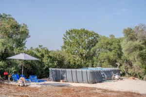 a swimming pool with chairs and an umbrella at Chalet dimora tra gli ulivi in Ostuni