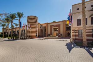 a building with palm trees and flags in front of it at Marina Resort Port Ghalib, a member of Radisson Individuals in Port Ghalib