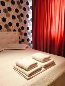 a bed with towels on it with a red curtain at GOLDEN APARTMENT- Militari Residence Bucharest in Dudu