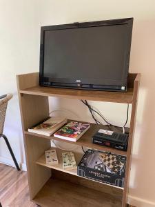 a television on a shelf with dvds and books at Hospedaje entre ríos Caipulli in Ancud