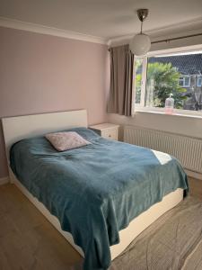a bedroom with a bed with a blue blanket and a window at Milan Casa in Winnersh
