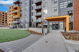 a large apartment building with a walkway in front at Elegant Downtown Condo with Balcony & Parking in Calgary