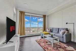 a living room with a couch and a tv at Elegant Downtown Condo with Balcony & Parking in Calgary