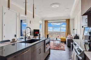 a kitchen with a view of a living room at Elegant Downtown Condo with Balcony & Parking in Calgary
