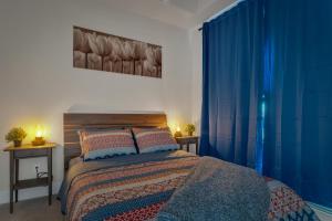 a bedroom with a large bed with blue curtains at Elegant Downtown Condo with Balcony & Parking in Calgary