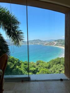 a view of a beach from a window at Luxury Residence at Vista Bay 103 in Zihuatanejo +14 photos