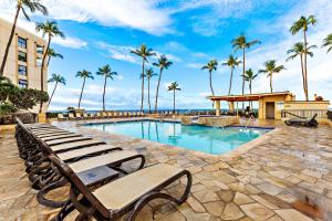 a swimming pool with a bench and palm trees at Sugar Beach 233 in Kihei