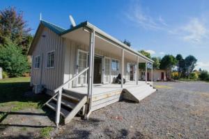 a small house with a porch with a person sitting on it at Grace Cottage in Turangi