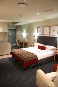 a hotel room with a large bed and a kitchen at Bentleys Motor Inn in Palmerston North