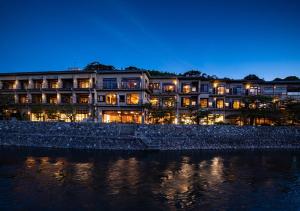 a hotel is lit up at night next to the water at Hanayashiki Ukifune-en in Uji