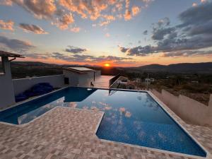 a pool on the roof of a house with a sunset at Flat por do Sol in Tiradentes