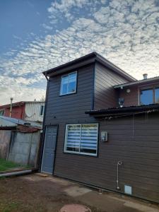 a brown house with a blue door and windows at Cabaña totalmente equipada in Viña del Mar