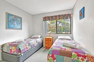 a bedroom with two beds and a window at Foreshore Paradise Nelson Bay in Nelson Bay
