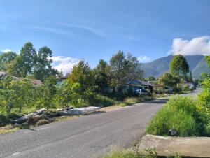 an empty road in a village with mountains in the background at LovKend in Ruteng
