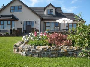 a house with a stone wall and an umbrella at Inishowen Lodge B&B in Moville