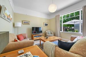 Una sala de estar con un sofá y un televisor. en Greenwood Cottage - Close to CBD, Leafy Backyard, en Bathurst