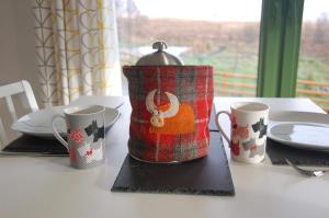 a tea pot sitting on a table with two mugs at Glas Beag in Spean Bridge
