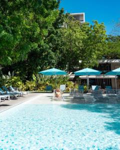 einen Pool mit blauen Sonnenschirmen, Stühlen und Tischen in der Unterkunft Tambuli Seaside Residences Buyong Road Maribago Lapu Lapu City in Cogon