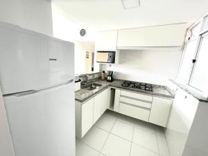 a white kitchen with white cabinets and a refrigerator at Luz do Sol até 10 Pessoas com Ar Condicionado in Arraial do Cabo