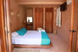 ein Schlafzimmer mit einem weißen Bett mit blauen Kissen in der Unterkunft Hotel Rinconcito de Mazunte in Santa María Tonameca