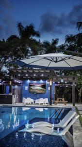 a pool with a blue umbrella and white chairs at Lake Of Dreams Miami House in Miami