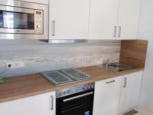 a kitchen with white cabinets and a sink and a microwave at Ferienwohnung im Erdgeschoss in Neßmersiel in Neßmersiel +21 photos
