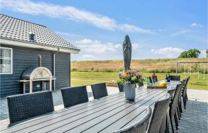 a wooden table with chairs and an umbrella at Awesome Home In Grenaa With Sauna in Grenå +38 photos
