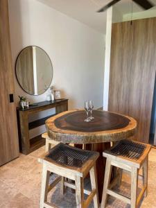 a wooden table with two stools and a mirror at Penthouse cerca de la playa in Tulum