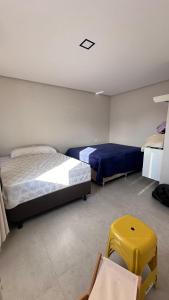 a bedroom with two beds and a yellow stool at Mansão Moraes - em Itacimirim Linha Verde in Camacari
