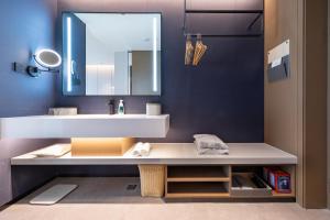 海口市にあるAtour Hotel Haikou Binhai Avenue Xixiu Beachの白い洗面台と鏡のあるバスルーム