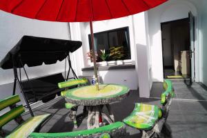 une table et des chaises avec un parasol rouge dans l'établissement London House Phuket, à Kata Beach