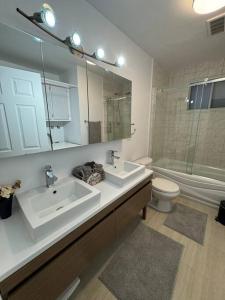 a bathroom with two sinks and a toilet and a mirror at Ste-Rose 2 bedroom apt in Laval