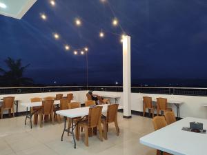 a person sitting at tables on a balcony at night at DJ Hotel in Raha