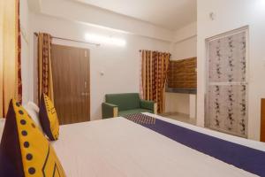 Habitación con cama y silla verde en SPOT ON Hotel Om Kanha, en Bilāspur