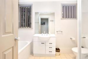 a white bathroom with a sink and a tub and a toilet at Close to Jimmys Beach in Hawks Nest +16 photos