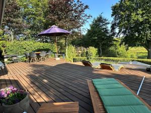 a wooden deck with a table and an umbrella at Amazing Home In Tikøb W- in Tikøb